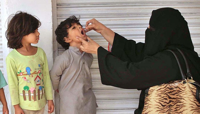 A female polio health worker administers polio drops to a child during the anti-polio vaccination campaign aimed at eradicating polio in the provincial capital. — AFP