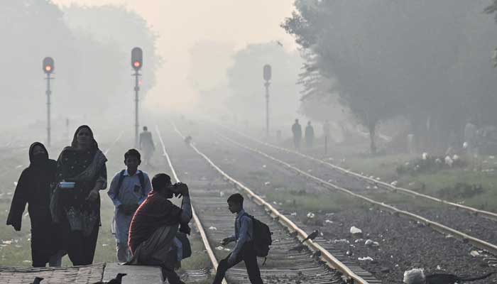 A school boy cross a railway track amid smoggy conditions in Lahore on November 4, 2024. — AFP