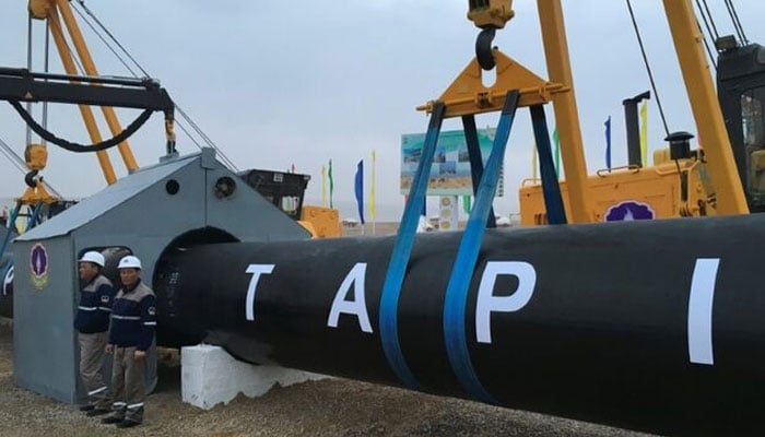 Workers stand near a gas pipe during the launching ceremony of construction work of the TAPI project on the Afghan section of a natural gas pipeline that will link Turkmenistan through Afghanistan to Pakistan and India, near the town of Serhetabat, Turkmenistan February 23, 2018. — Reuters