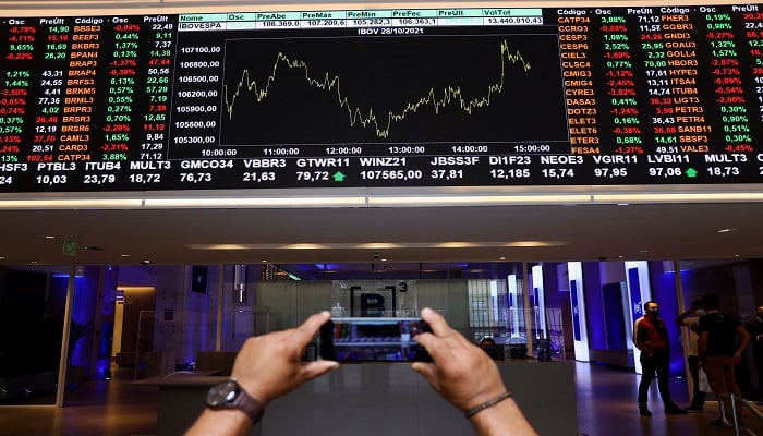 A man takes a picture with his phone of an electronic board showing the recent fluctuations of market indices on Brazils B3 Stock Exchange in Sao Paulo, Brazil October 28, 2021.— Reuters