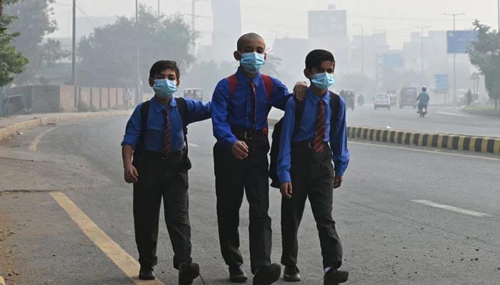 School boys wear masks as they walk along a road amid heavy smog in Lahore on October 29, 2024. — AFP