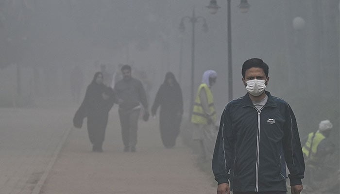 People walk around a park amid heavy smoggy conditions in Lahore on November 7, 2024. — AFP