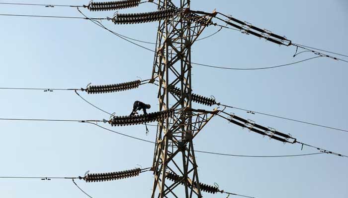 A technician works on porcelain insulators on power transmission tower in Karachi on December 7, 2018. — Reuters