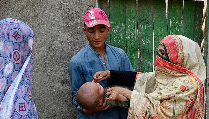 This photograph taken on October 5, 2024 shows a health worker (R) administering polio drops to a child during a door-to-door poliovirus vaccination campaign on the outskirts of Peshawar. — AFP