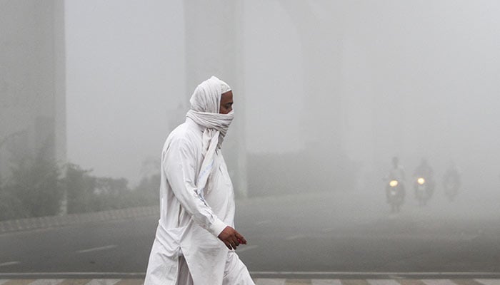 A man covers his face with a scarf to avoid smog as he walks along a road in Multan, Pakistan November 10, 2024. — Reuters