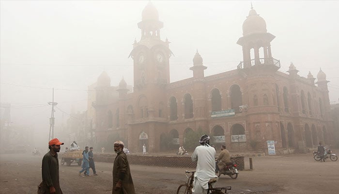 Commuters move along a street amid heavy smoggy conditions in Multan on November 9, 2024. — AFP