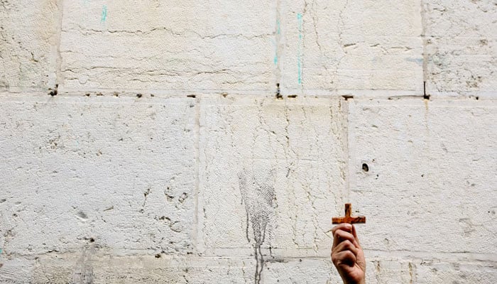 A worshipper holds up a cross during the Good Friday procession at the Via Dolorosa in Jerusalems Old City, March 29. — Reuters