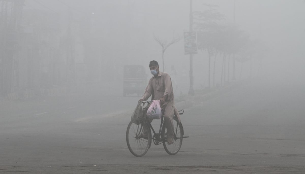 A man wears a mask to avoid smog while he rides on a bicycle along a road in Multan on November 9, 2024. — Reuters