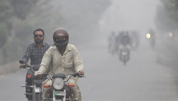 People ride on motorbikes amid smog on a road in Multan, Pakistan November 12, 2024. — Reuters