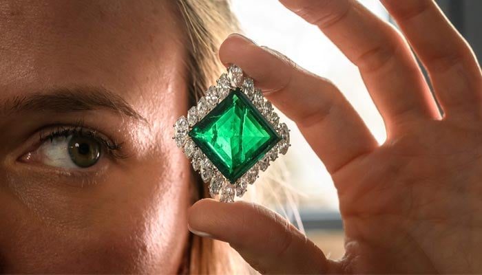 A Christies employee poses with The Aga Khan Emerald during a press preview in Geneva, on November 7, 2024. — AFP