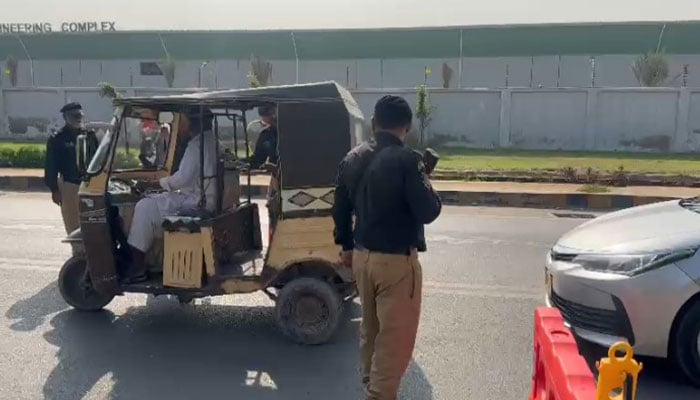 Police personnel stop commuters at a checkpoint on a road leading towards Karachi airport, on November 13, 2024. — Reporter