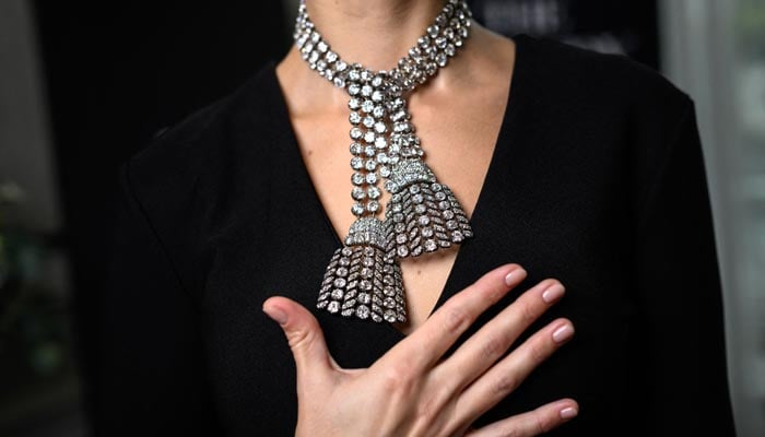 A woman wearing the 18th century diamond jewel necklace, poses during a press preview at Sothebys auction house in Geneva, on November 7, 2024. — AFP