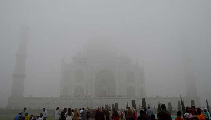 Visitors look toward the Taj Mahal through morning air pollution and fog in Agra, India, November 14, 2024. — Reuters