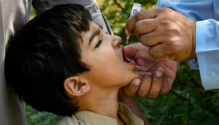 A health worker administering polio drops to a child on the outskirts of Peshawar, on October 5, 2024. — AFP