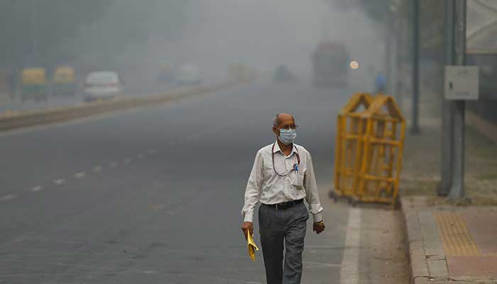 A man wearing a mask walks on a road amid a smoggy morning in New Delhi, India on November 13, 2024. — Reuters