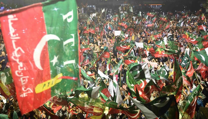 PTI supporters wave party flags as they take part in a rally in Karachi on April 10, 2022. — AFP