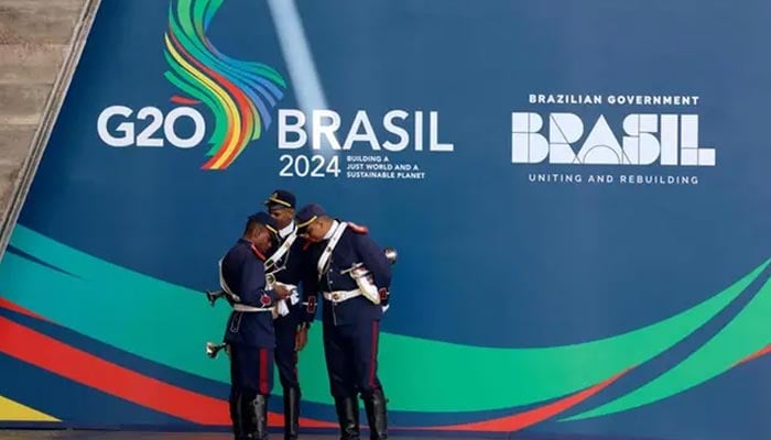 Members of the honour guard check a phone before the arrival of delegates on the first day of the G20 Summit in Rio de Janeiro on November 18, 2024. — AFP