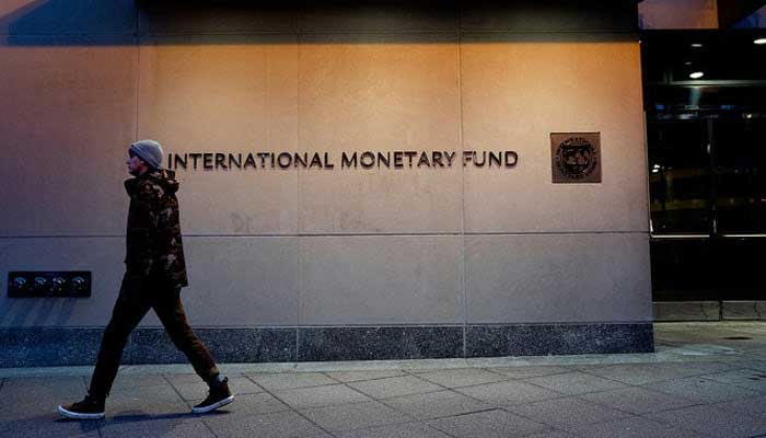 A  pedestrian walks past the International Monetary Fund headquarters in Washington, DC. — AFP/File