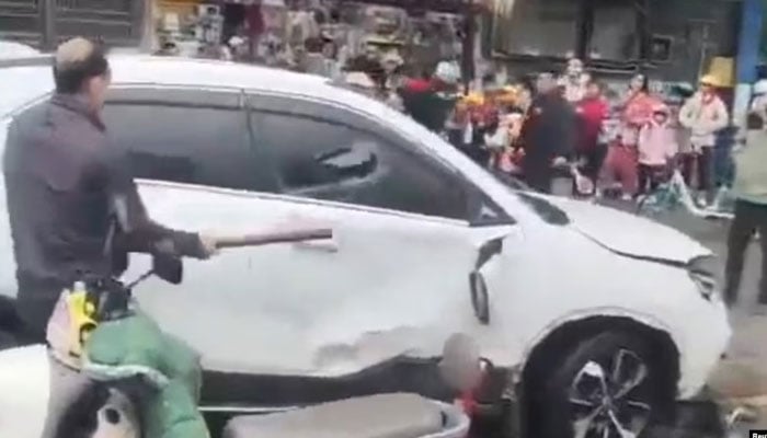 A man breaks a cars window following a vehicle collision outside a primary school in Changde, Hunan province, China in this screengrab obtained from social media video released November 19, 2024. — Reuters