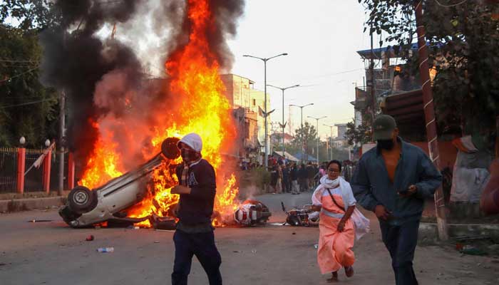 People run past burning vehicles of Indias Bharatiya Janata Party (BJP) MLA during a protest to condemn the alleged killing of women and children in Imphal, capital of India´s violence-hit northeastern state of Manipur on November 16, 2024. — AFP