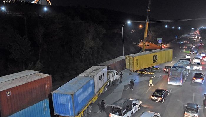 Workers place heavy shipping containers at Islamabad Highway near zero point for road block ahead of PTI protest in Islamabad — November 19, 2024. — Online