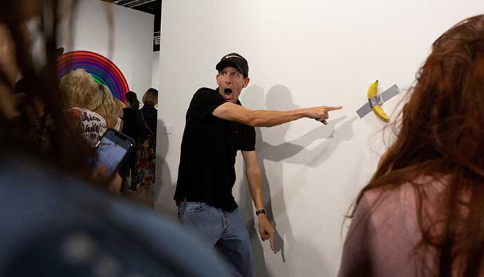 A man poses for a photo next to a banana attached with duct-tape that replaces the artwork Comedian by the artist Maurizio Cattelan, which was eaten by David Datuna, in Miami Beach, Florida, December 7, 2019. — Reuters