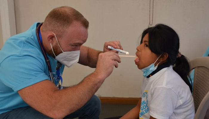 Representational image of a child getting her throat checked by a medical official. — Unsplash/file