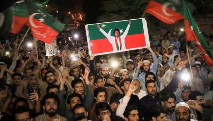 Supporters of PTI wave flags and chant in support of former prime minister Imran Khan during a rally in Peshawar on April 10, 2022. —Reuters