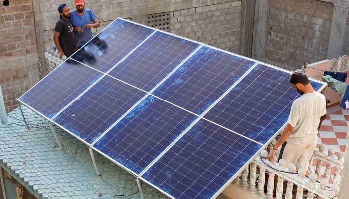 Technicians work on solar panels installed on the roof of a house in Karachi. — Reuters/File