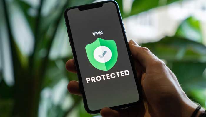 A representational image showing a person holding a mobile phone with VPN logo on screen. — Unsplash