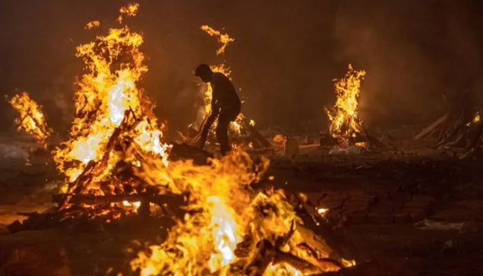 This undated photo shows people cremate the bodies at a crematorium in Delhi. — Reuters