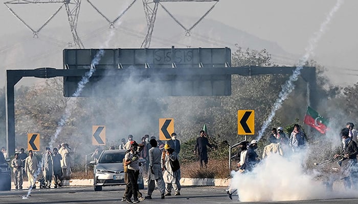 PTI workers attempt to throw back teargas shells fired by riot policemen as they protest during a march to Islamabad in Hasan Abdal in Punjab province on November 25, 2024. — AFP