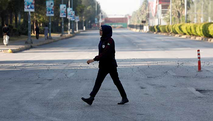 A police officer walks past a wire laid across a road to prevent an anti-government rally by the PTI in Islamabad on November 25, 2024. — Reuters