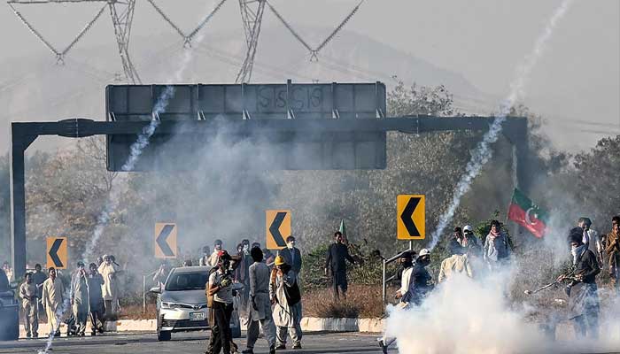 PTI workers attempt to throw back teargas shells fired by riot police as they protest during a march to Islamabad on November 25, 2024. — AFP