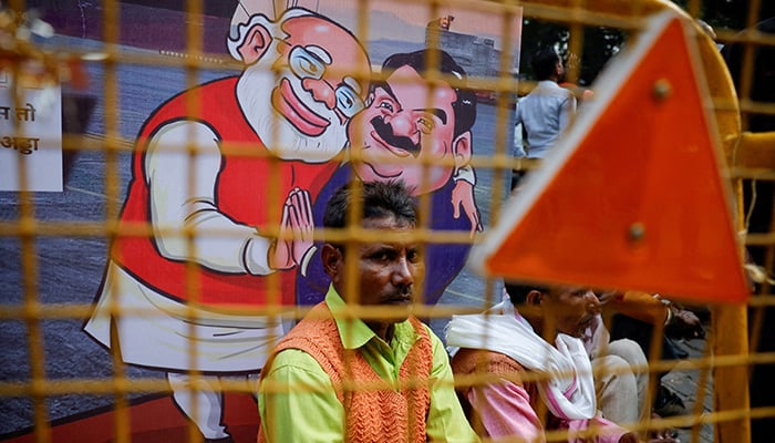 A man sits next to a poster put up during a protest by Indias main opposition Congress party against Indian billionaire Gautam Adani in New Delhi, India. — Reuters/File