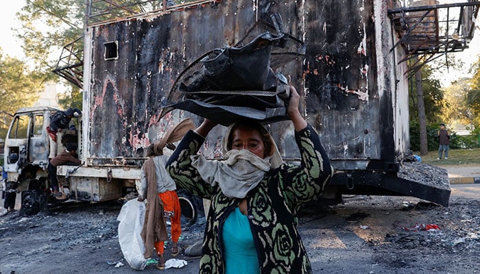 Women and children collect recyclables from the burnt truck used by Bushra Bibi after security forces launched a raid on supporters of PTI in Islamabad, Pakistan, November 27, 2024. — Reuters