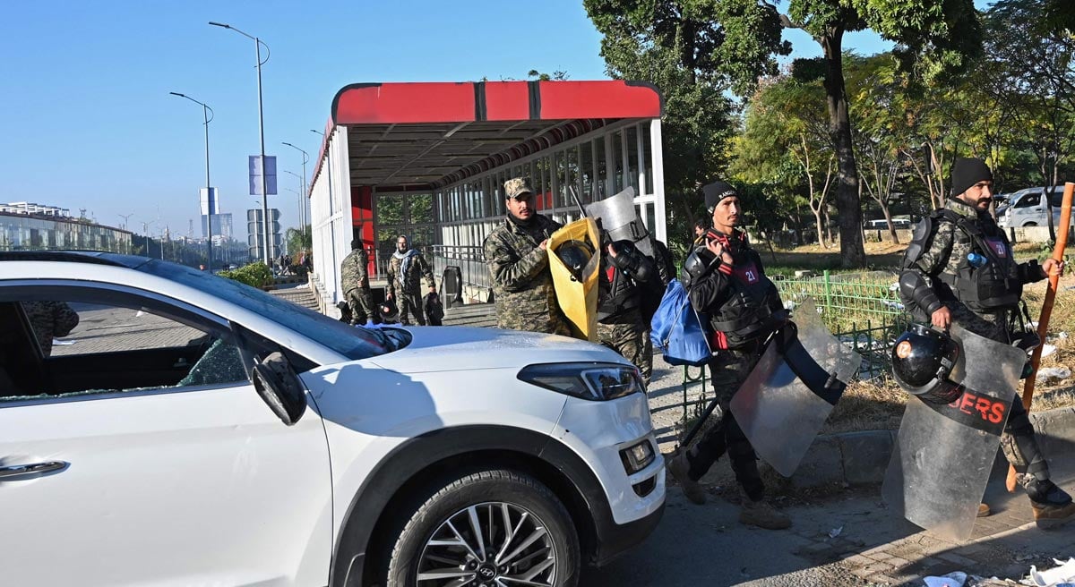 Paramilitary rangers walk past a damaged vehicle after a protest march by the supporters of jailed former prime minister Imran Khan near red zone area in Islamabad on November 27, 2024. — AFP