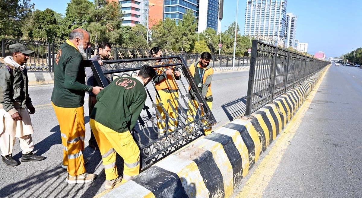 Workers installing the grills on divider of Jinnah Avenue which damaged following PTI protest in Islamabad on November 27, 2024. — APP