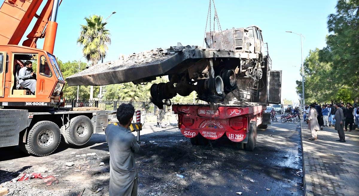 Officials busy removing the burnt container from the site at Jinnah Avenue following PTI protest in Islamabad on November 27, 2024. — APP