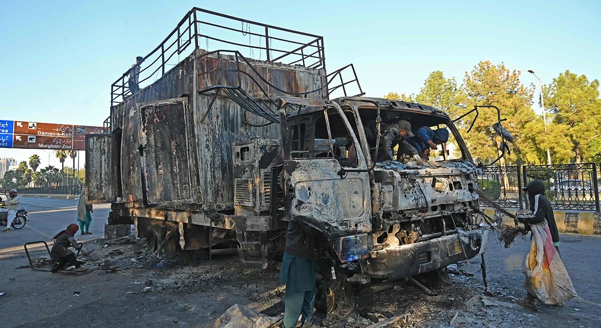 Ragpickers collect scraps from a burnout rally truck used by Bushra Bibi, the wife of Pakistan´s former prime minister Imran Khan, near the red zone area after a protest to demand Khan´s release, in Islamabad on November 27, 2024. — AFP