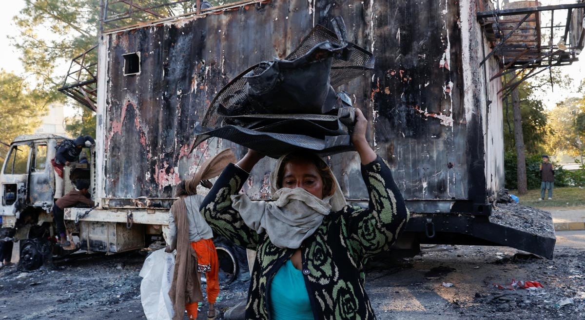 A woman carries recyclables from the burnt truck used by Bushra Bibi, wife of jailed former Pakistani Prime Minister Imran Khan, after security forces launched a raid on supporters PTI on Tuesday, in Islamabad, Pakistan, November 27, 2024. — Reuters