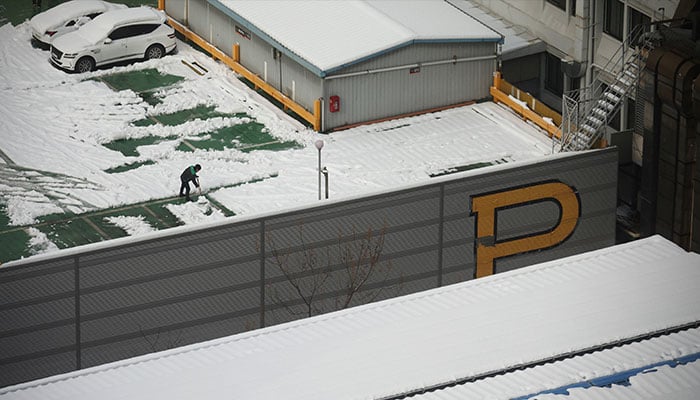 A man cleans up the rooftop of a building after a heavy snowfall in Seoul, South Korea, November 28, 2024. — Reuters