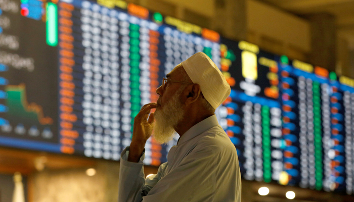 A stock broker reacts while monitoring the market on the electronic board displaying share prices during trading session at the PSX, in Karachi, on July 3, 2023. — Reuters