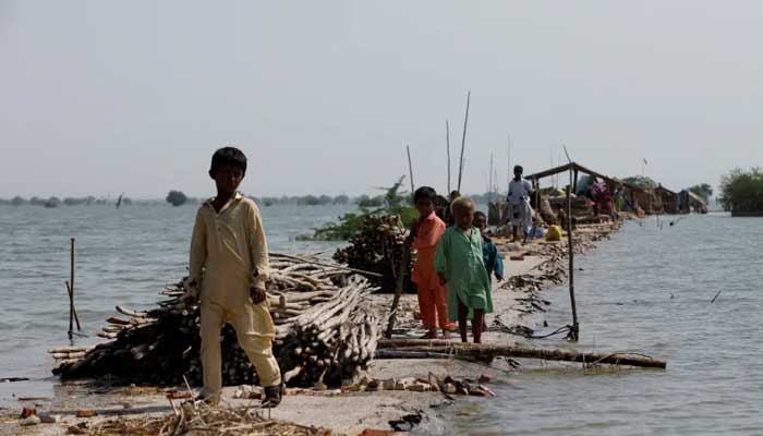 Children stand as their family takes refuge along a damaged road amid a flood, following rains and floods during the monsoon season in Bajara village, at the banks of Manchar lake, in Sehwan, September 6, 2022. — Reuters