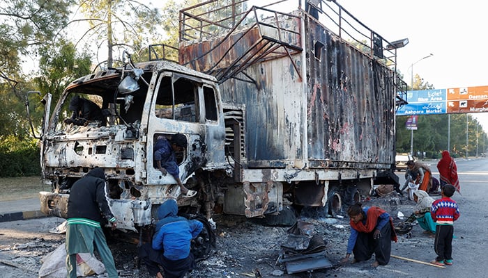 Women and children collect recyclables from the burnt truck used by Bushra Bibi, wife of jailed PTI founder Imran Khan, after the partys protest in Islamabad, November 27, 2024. — Reuters