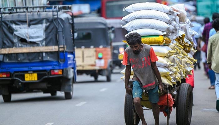 A labourer pulls a loaded handcart along a street at a wholesale market in Colombo, Sri Lanka, July 4, 2023. — AFP