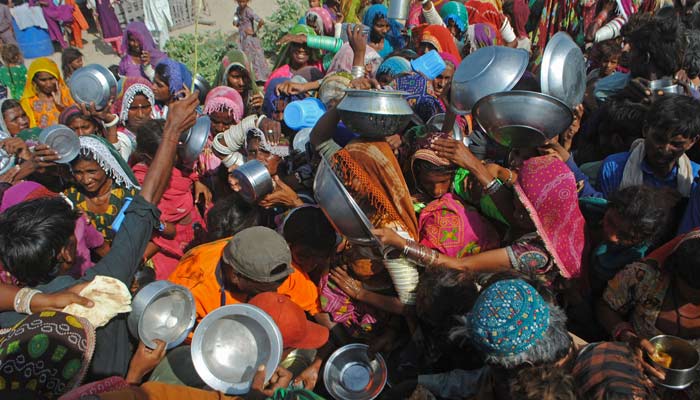 Internally displaced people gather to receive free food near their makeshift camp in the flood-hit Chachro of Sindh province on September 19, 2022. — AFP