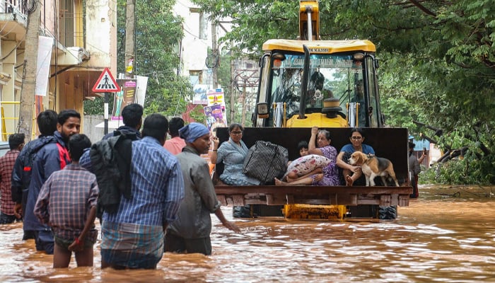 People move through a flooded street after heavy rainfall in Puducherry on December 1, 2024. — AFP