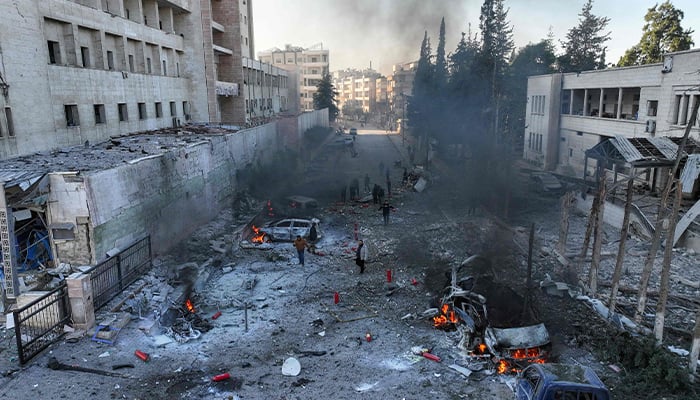 An aerial picture shows people try to extinguish fires following an airstrike that targeted Syria´s rebel-held northern city of Idlib on December 2, 2024. — AFP