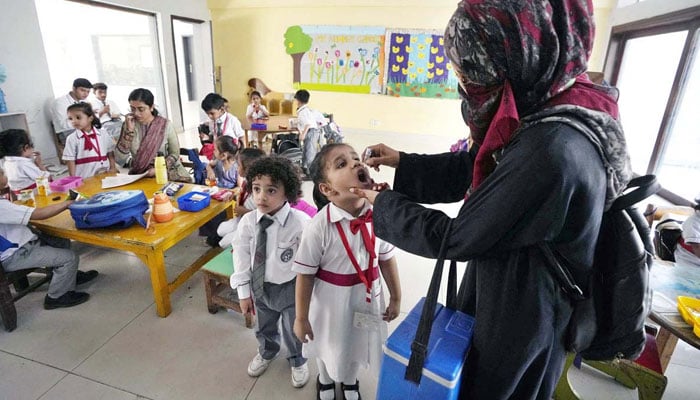 A female health worker administers polio drops to school children in Karachi on October 28, 2024 during a vaccination drive aimed at eradicating polio in Pakistan. — APP